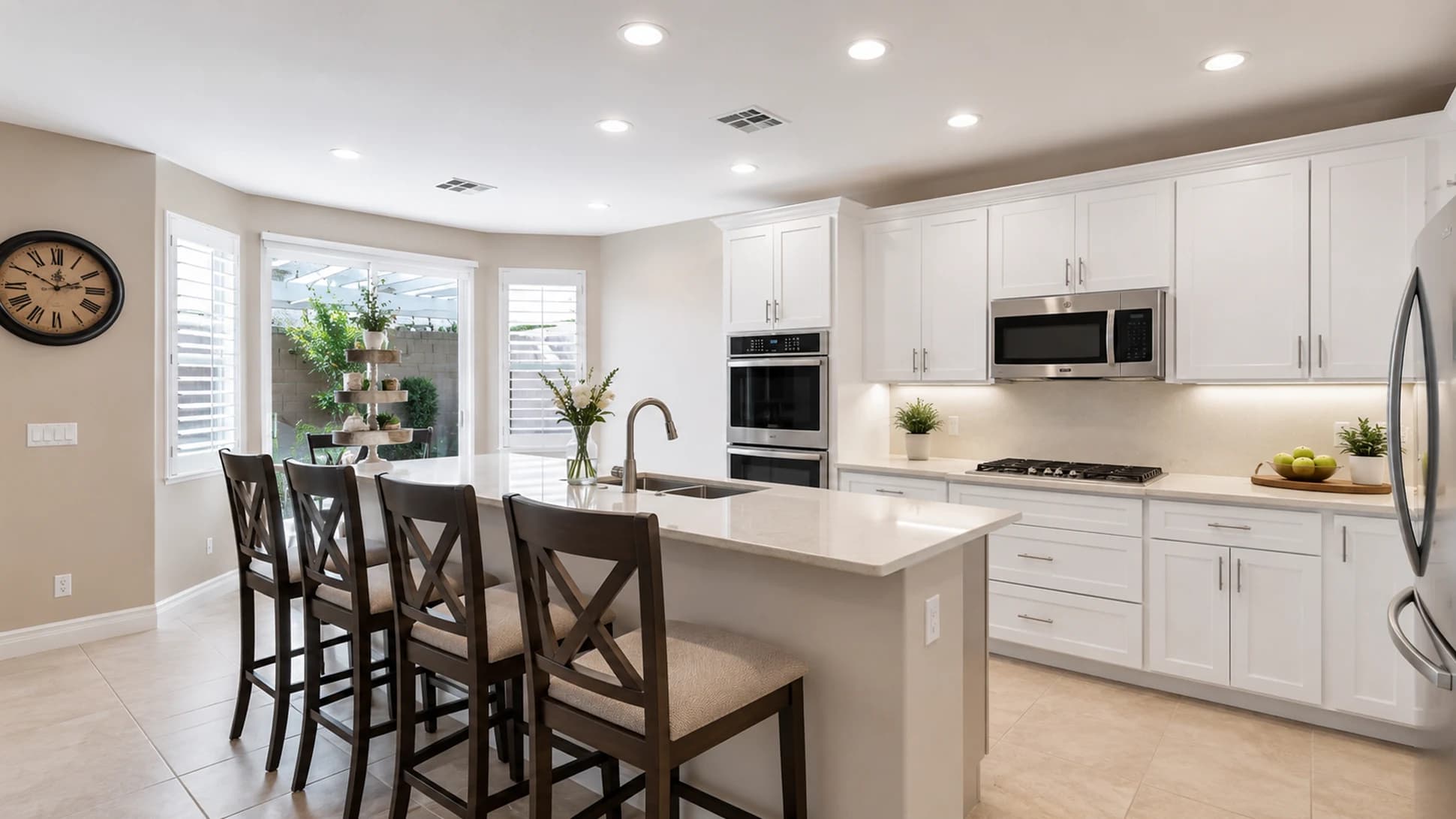 Finished kitchen after the prefab cabinet remodel with white raised-panel cabinets, larger single-level island, leathered quartz, and updated lighting