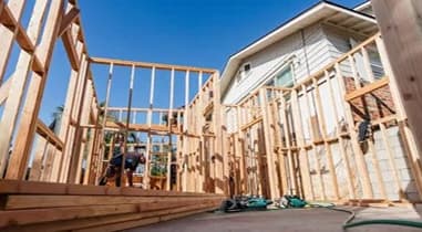 Wood framing for a small building beside an existing house under construction