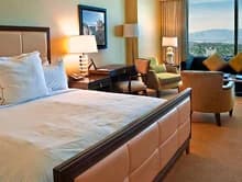 Furnished bedroom with a bed, armchair, and large windows.