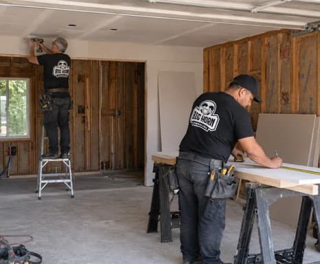 Two Big Horn Remodeling crew members working inside an unfinished garage.