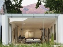 Compact studio-style living space with open glass doors and a furnished interior.