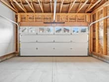 Unfinished garage with exposed wood framing and a closed overhead door.