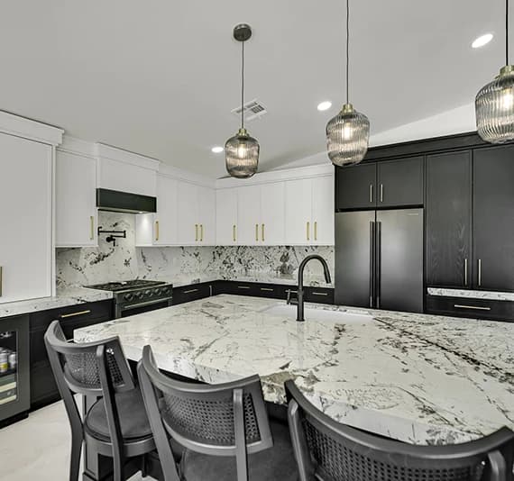 Recent Las Vegas home remodel - custom kitchen with two-tone cabinetry, large stone island, full-height backsplash, pendant lighting, and black fixtures