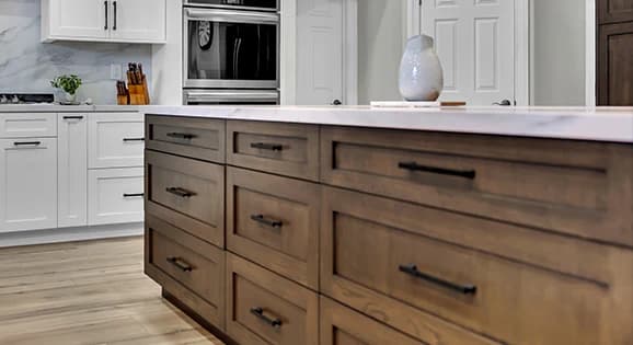 Semi-custom kitchen cabinet island with wood drawer storage and white perimeter cabinets
