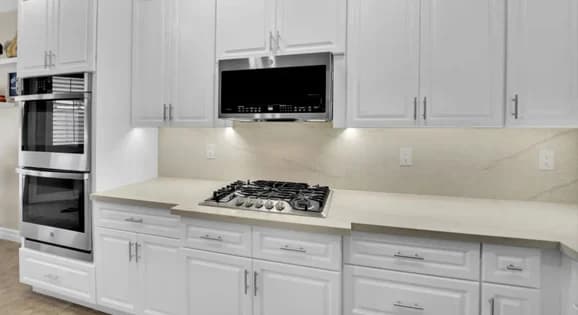 White stock or prefab kitchen cabinets around range, microwave, and wall oven