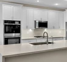 Semi-custom white kitchen cabinets with island, wall oven, and appliance planning