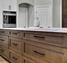 Custom wood island cabinets coordinated with white perimeter cabinets and appliances