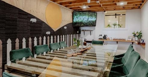 Office break room with a communal table, green chairs, kitchenette and wall mural.