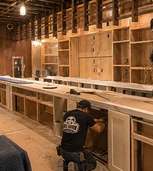 Contractor reviewing plans at a worktable in an unfinished commercial interior.