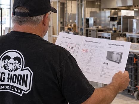 Big Horn Remodeling team member reviewing a floor plan in an unfinished commercial interior.