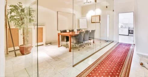 Glass-walled meeting room with a long wood table and office finishes.