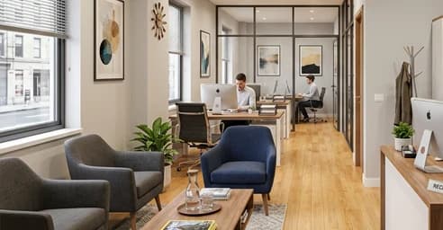 Office lounge and workstations separated by glass partitions.