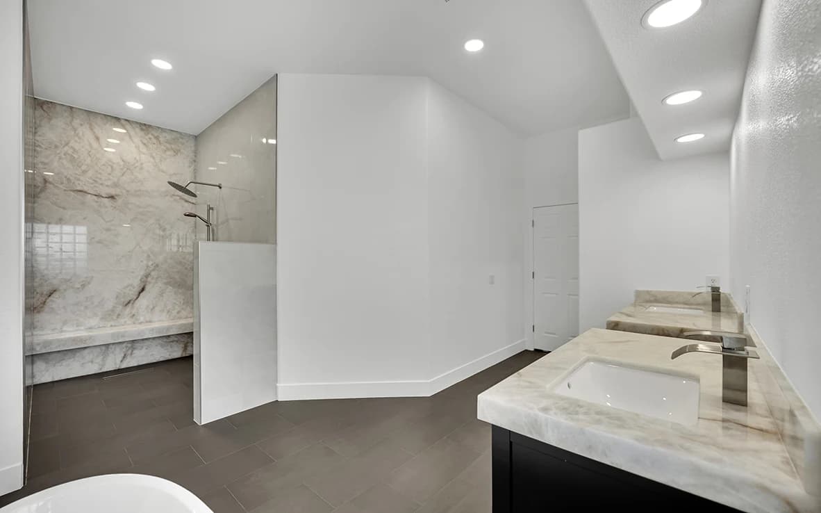 Primary bathroom remodel with curbless onyx shower, double vanity, freestanding tub, and charcoal gray floor tile