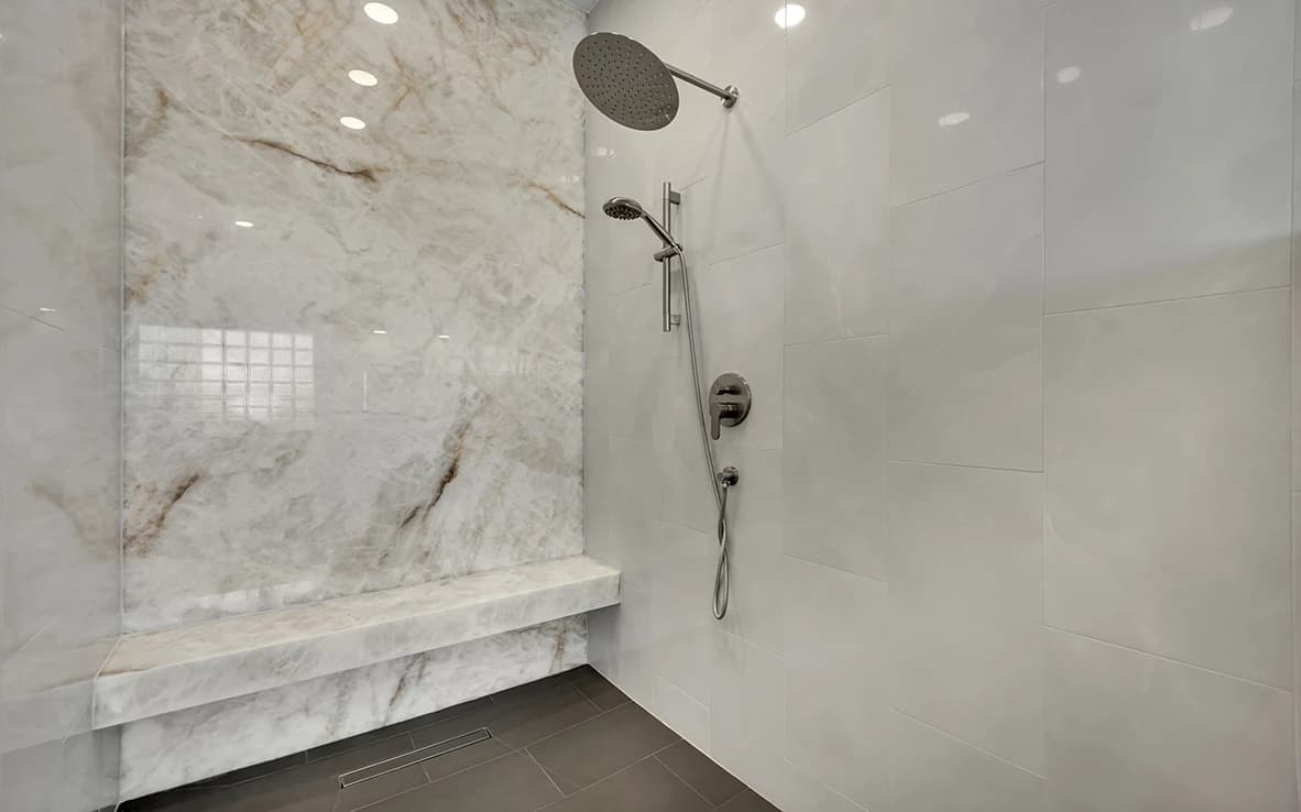 Honey Amber Onyx shower wall with rain head, handheld wand, bench, and curbless tile floor