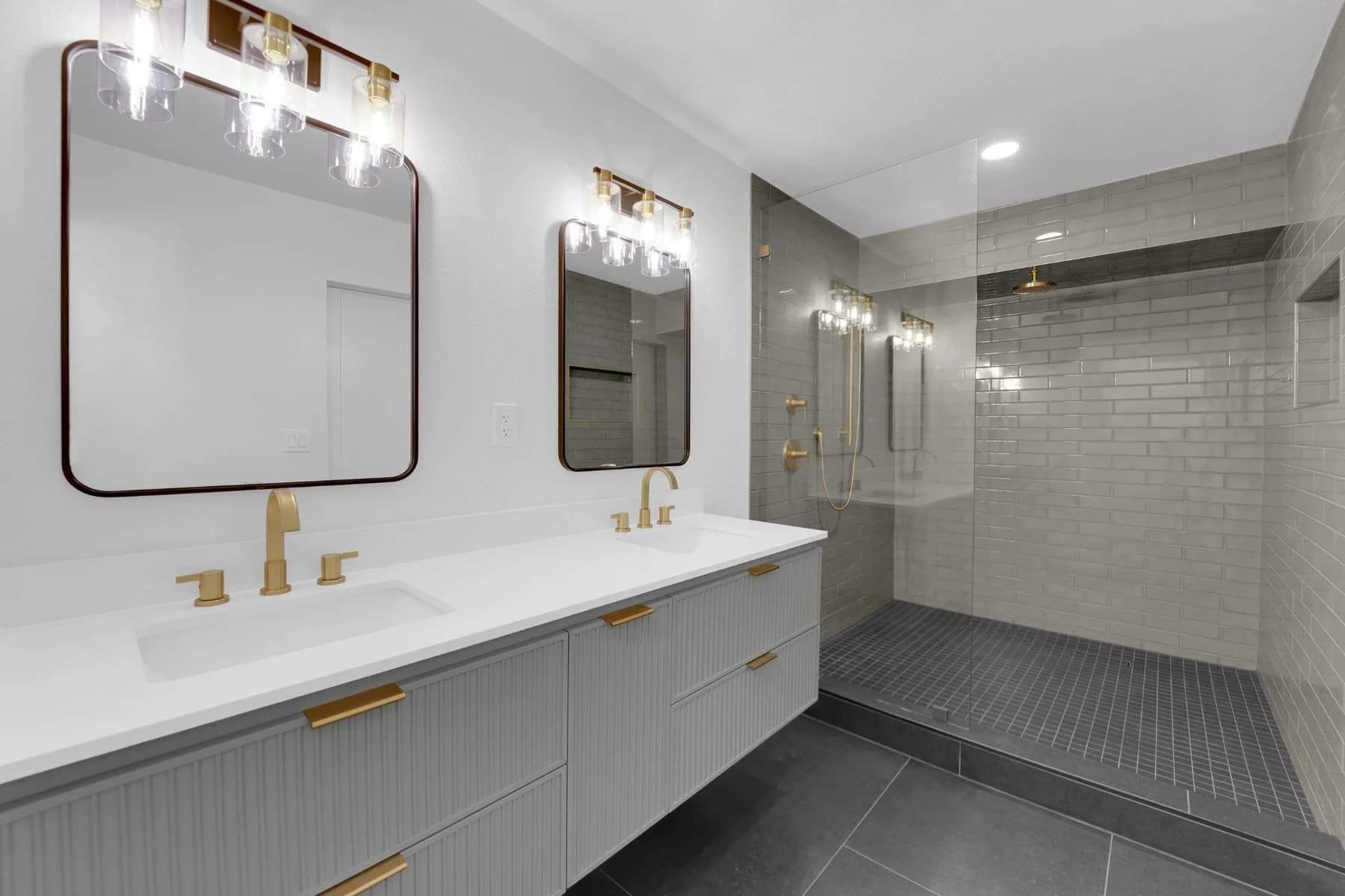 Completed Downtown Las Vegas bathroom remodel with floating gray double vanity, brushed-gold fixtures, and expanded green tile shower