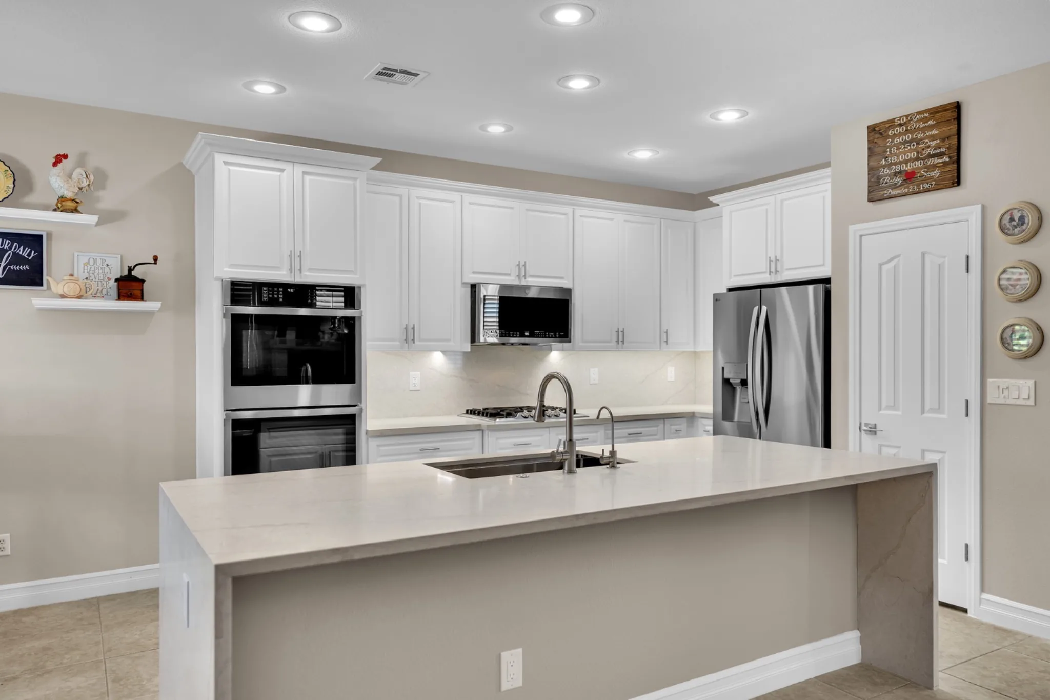 Prefab kitchen remodel with white raised-panel cabinets, leathered quartz countertops, enlarged island, and stainless appliances
