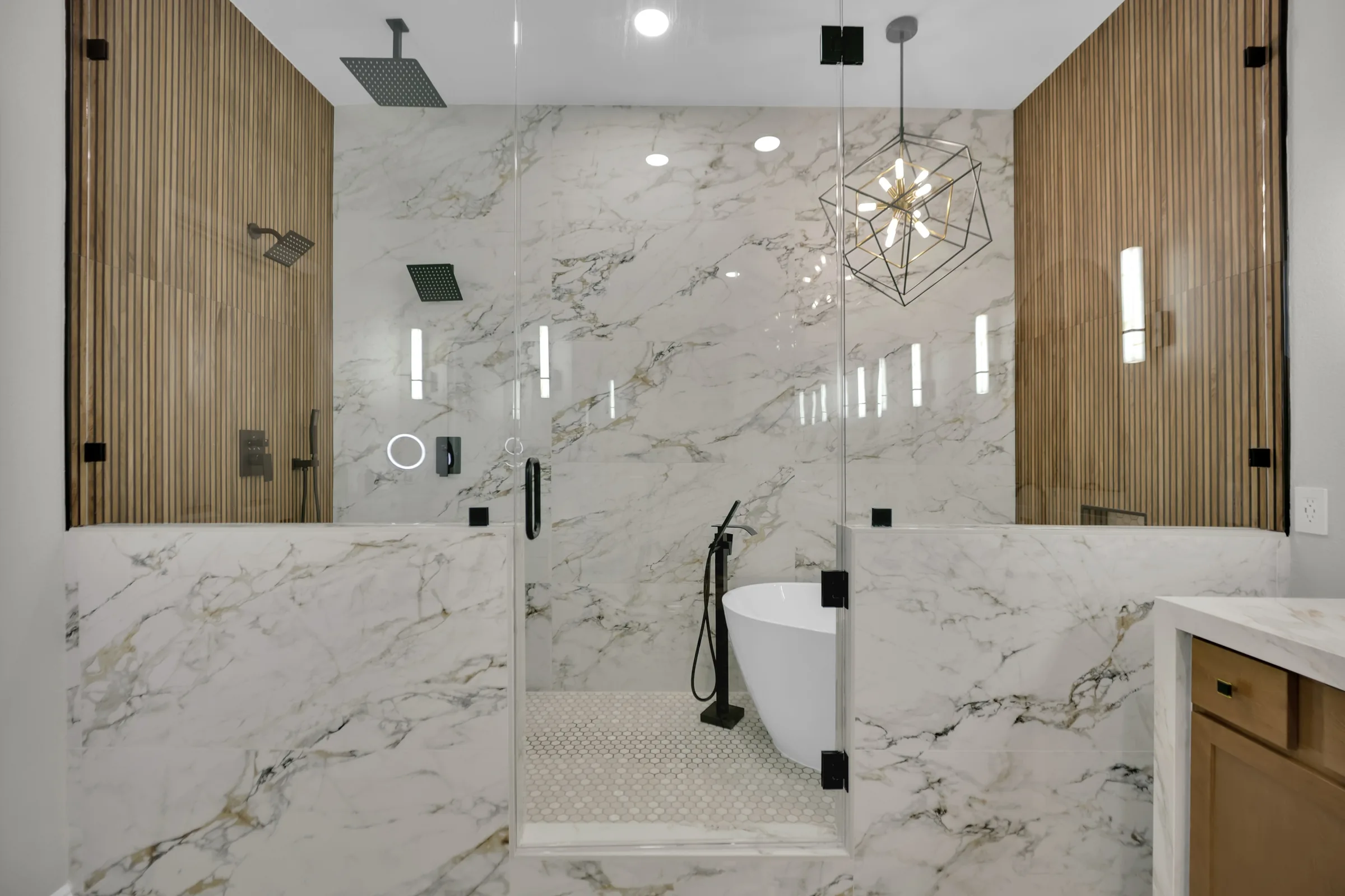 Wet room with a freestanding tub, two pony walls, fluted wood-look tile, and clear glass.