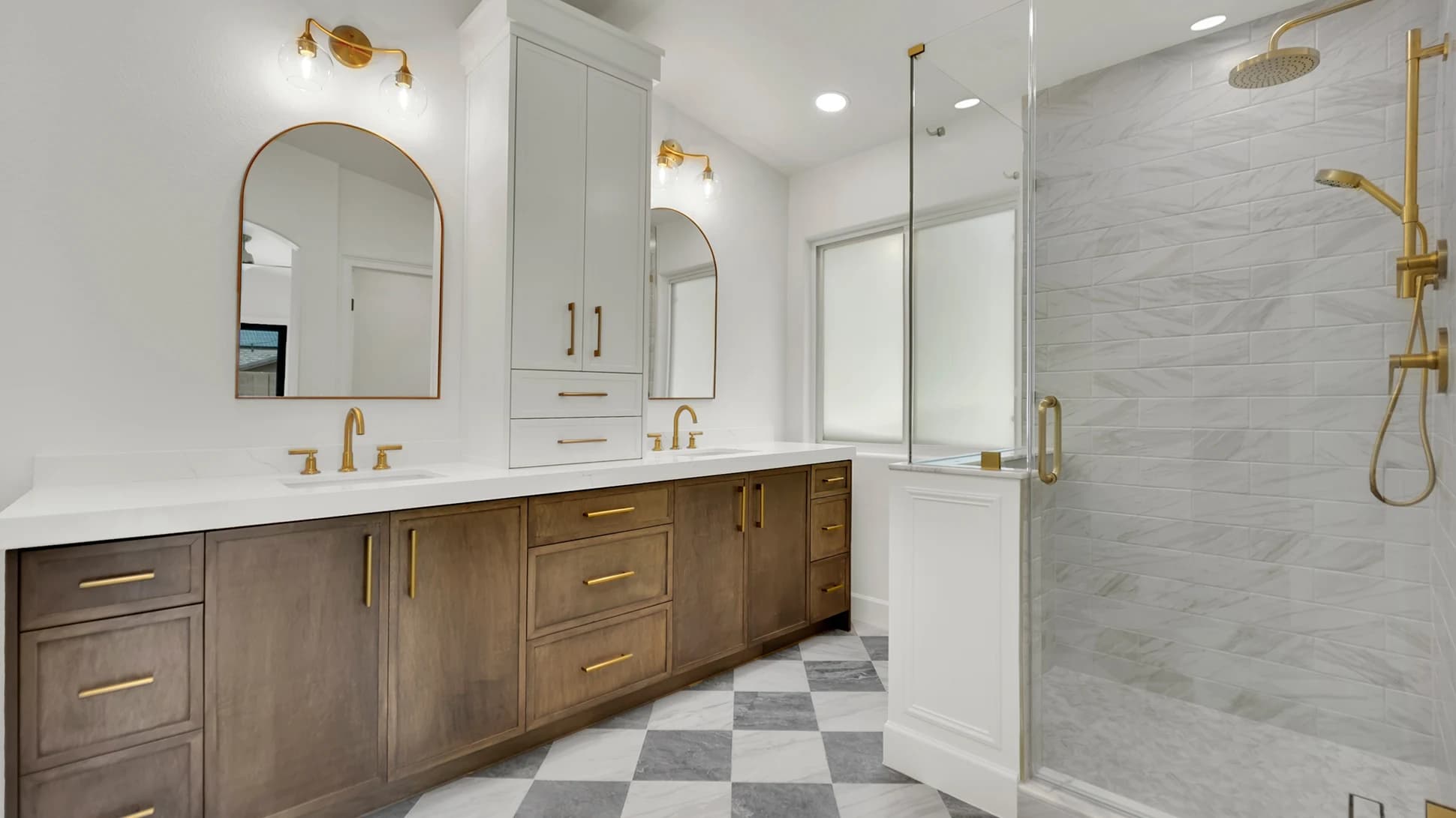 Finished primary bathroom after the remodel with enlarged marble shower, custom glass, white oak vanity, quartz countertop, gold fixtures, and checkered marble floor