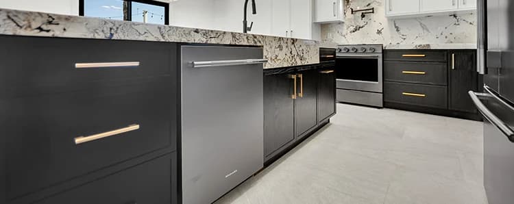 Finished kitchen with dark flat-panel cabinets, white upper cabinets, stone countertop, slab backsplash, black faucet, and stainless range