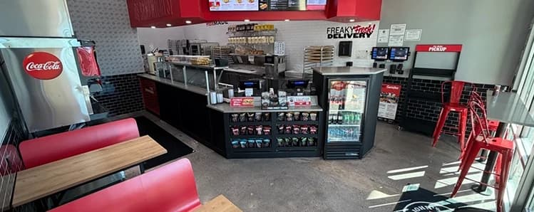 Completed Jimmy John's dining area with red booth seating, service counter, beverage cooler, pickup station and menu boards.