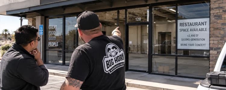 Two Big Horn Remodeling team members review a vacant second-generation restaurant storefront with a restaurant-space-available sign.