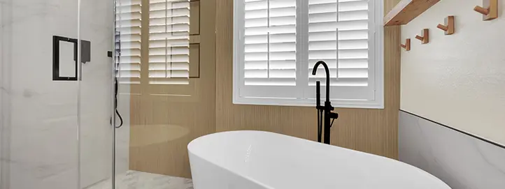 Bathroom with freestanding tub, glass shower panel, wood accent wall, and black fixtures