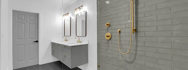 Bathroom remodel with gray subway shower tile, brushed gold fixtures, glass panel, and vanity