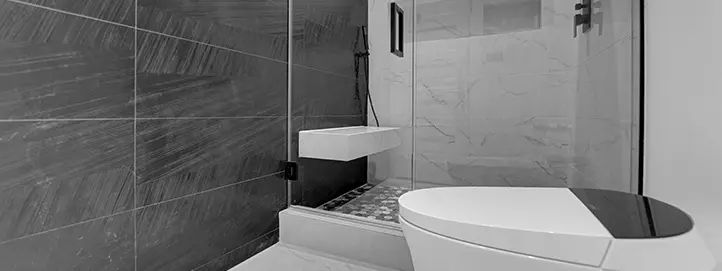 Bathroom with gray tiled shower wall, shower bench, freestanding tub, and glass partition
