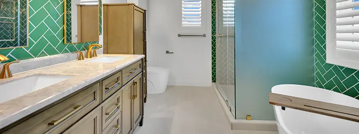 Bathroom with green herringbone tile, double vanity, glass shower, and freestanding tub
