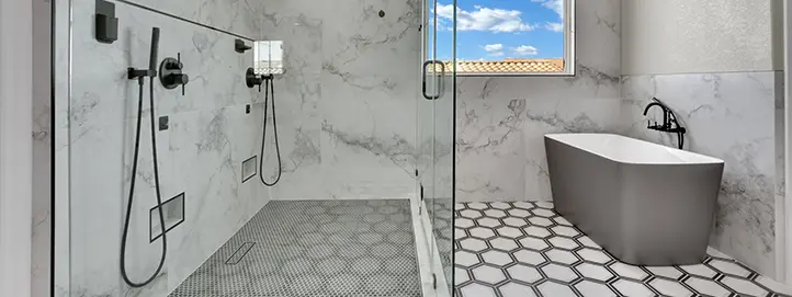 Wet-room style bathroom with marble-look shower tile, glass enclosure, freestanding tub, and patterned floor