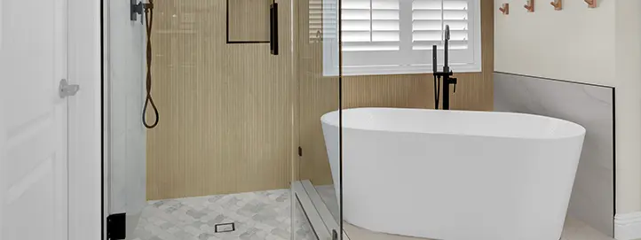 Bathroom with wood accent shower wall, glass enclosure, freestanding tub, and black shower fixtures