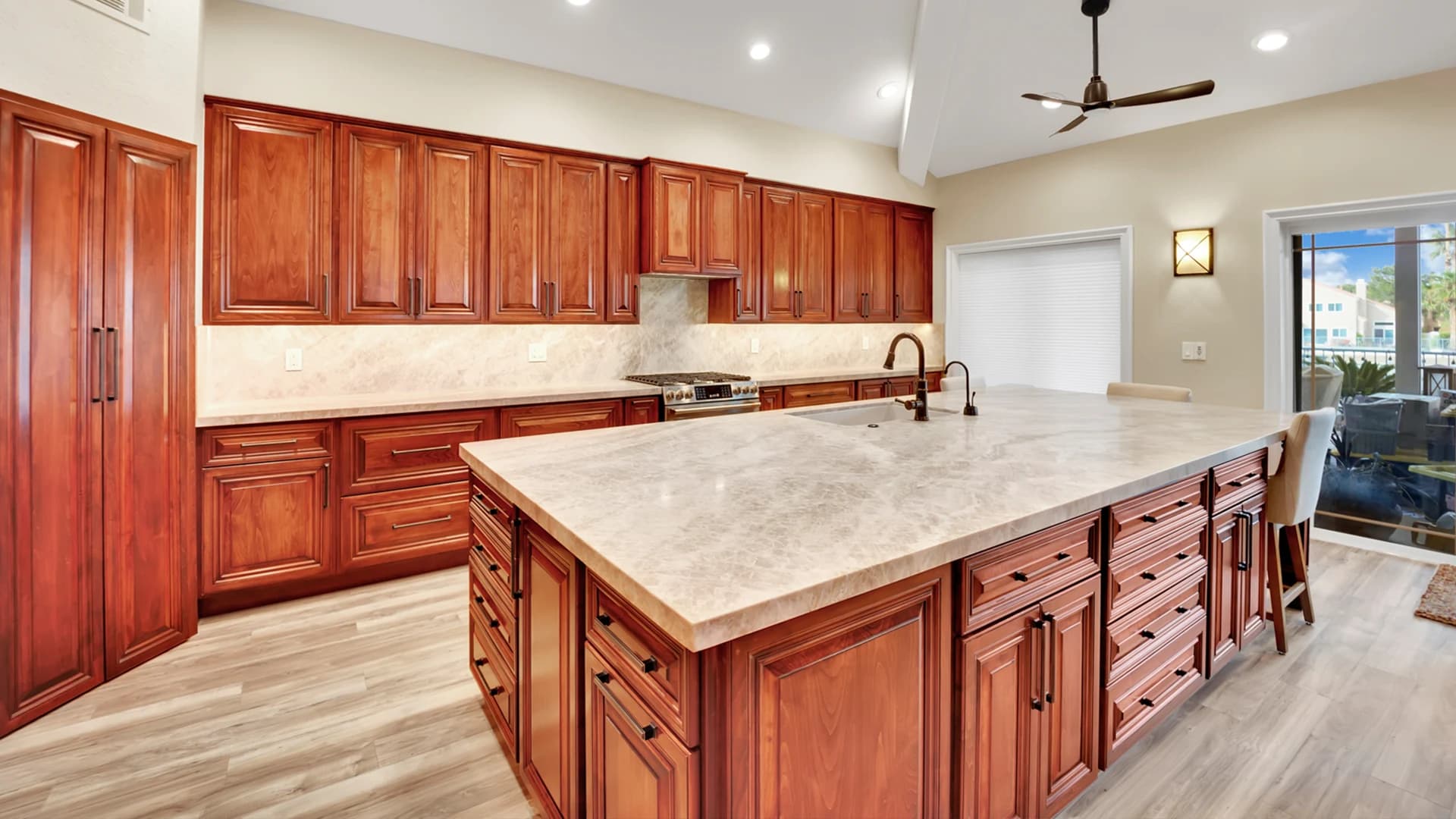 Finished Las Vegas kitchen remodel with red wood cabinets, large island, and stone countertops