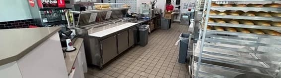 Fast-casual restaurant kitchen with a service counter, prep line and bakery racks