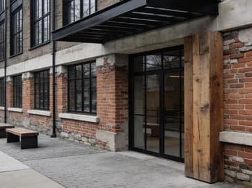 Brick storefront with a black-framed glass entrance opening onto a paved walkway.