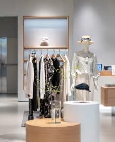 Clothing-store display with mannequins, hanging garments and an open customer aisle.