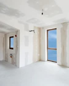 Unfinished suite with patched drywall, open doorways and a bare floor.