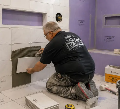 Tile installer setting wall tile beside a shower niche