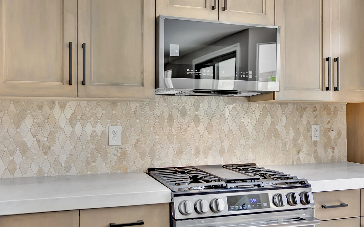 Close view of range, microwave, marble backsplash, and sample-matched maple upper cabinets