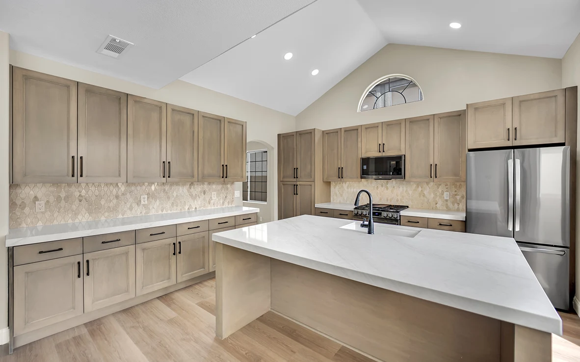 Finished Cantabria kitchen with sample-matched maple cabinets, Briella Gold quartz island, island sink, and marble backsplash