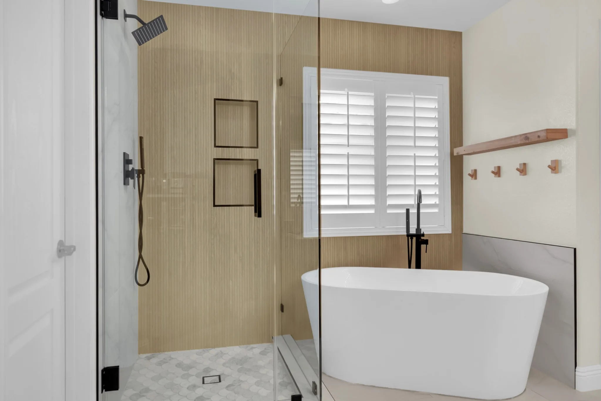 Completed upstairs primary bathroom remodel with expanded shower, freestanding tub, wood-look tile wall, and custom frameless glass