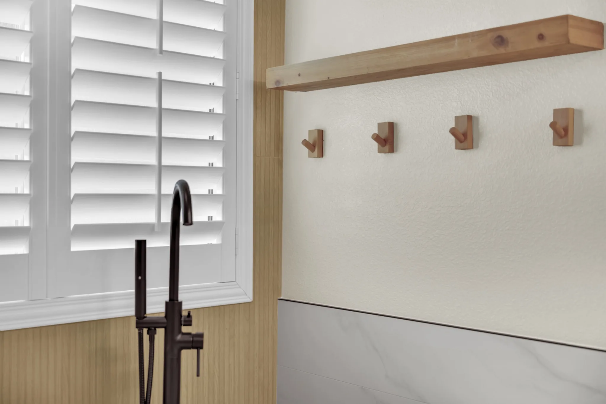 Northwest Las Vegas primary bathroom remodel showing expanded shower glass, freestanding tub, plantation shutters, and wood-look tile behind the tub
