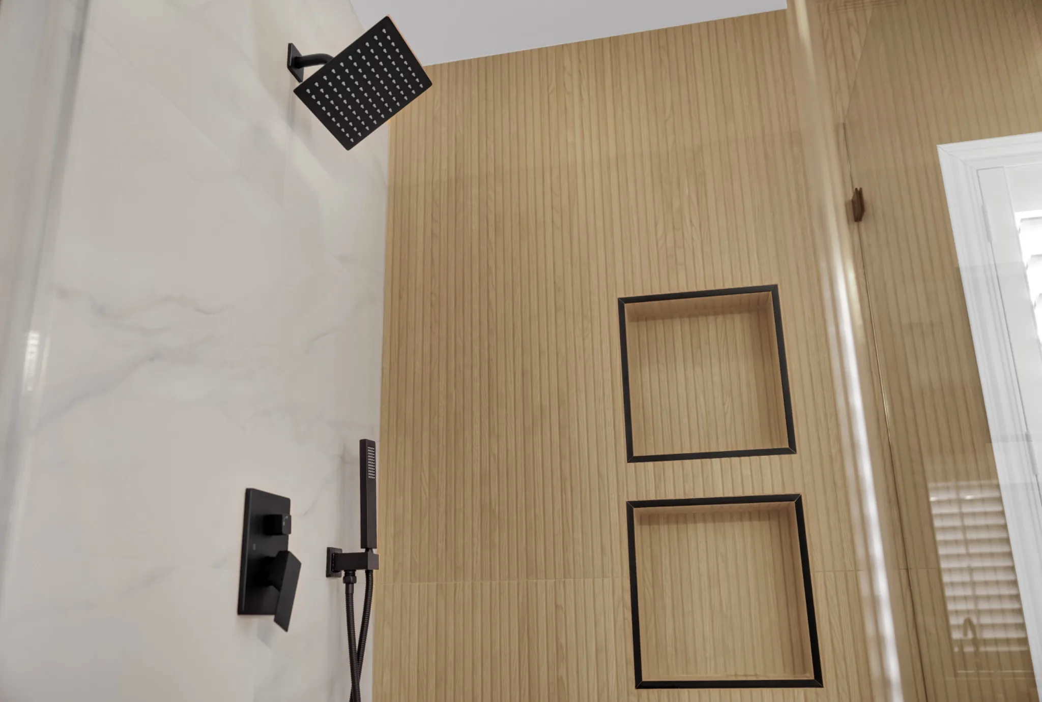 Custom shower remodel with wood-look tile accent wall, black-trimmed shower niches, matte black rain head, and handheld shower wand