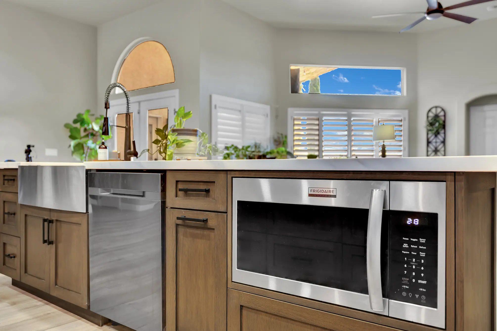 Centennial Hills kitchen island detail with dishwasher, microwave, farmhouse sink, custom cabinets, and quartz countertop