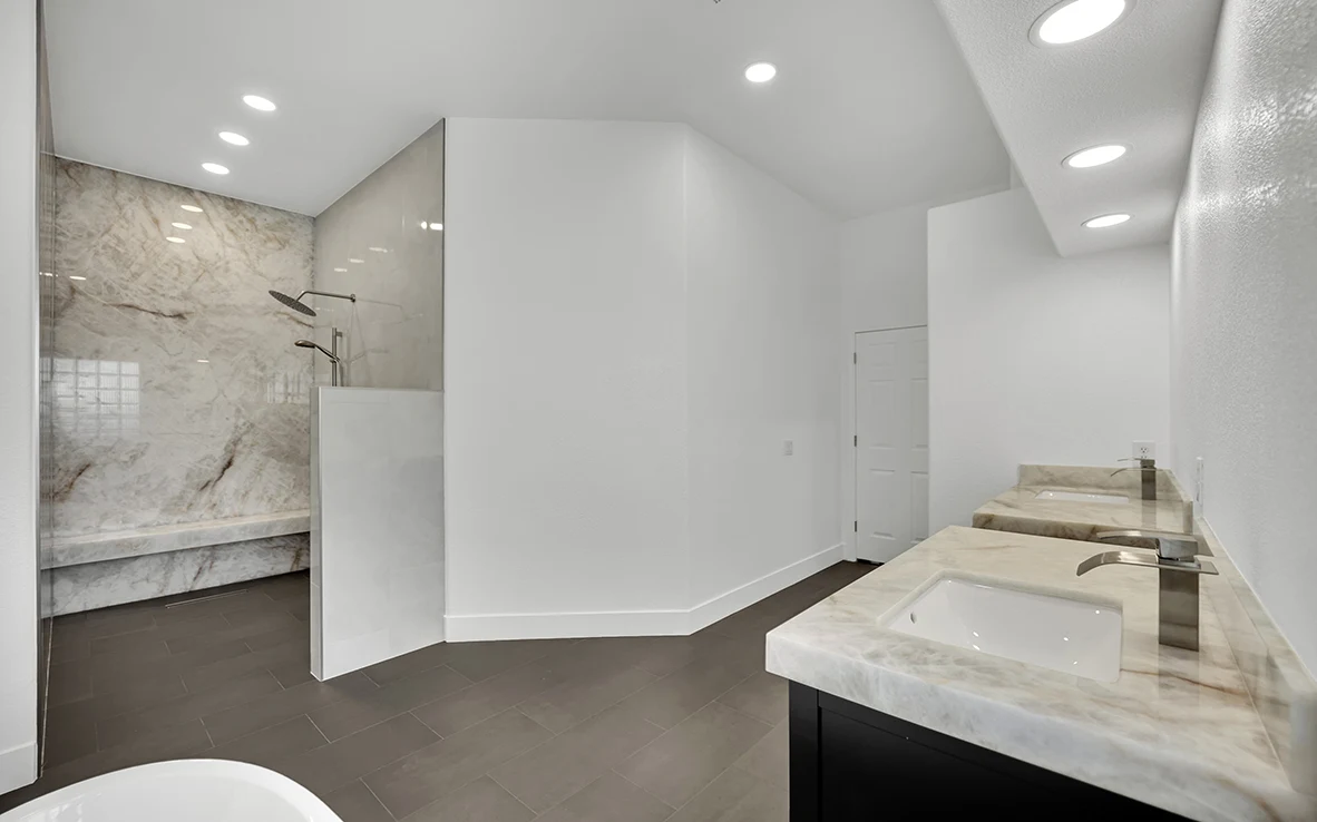 Primary bathroom remodel with curbless onyx shower, double vanity, freestanding tub, and charcoal gray floor tile