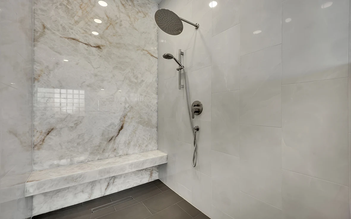 Honey Amber Onyx shower wall with rain head, handheld wand, bench, and curbless tile floor