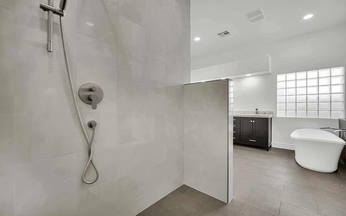 Shower valve and handheld wand detail with charcoal gray tile floor in a curbless primary shower