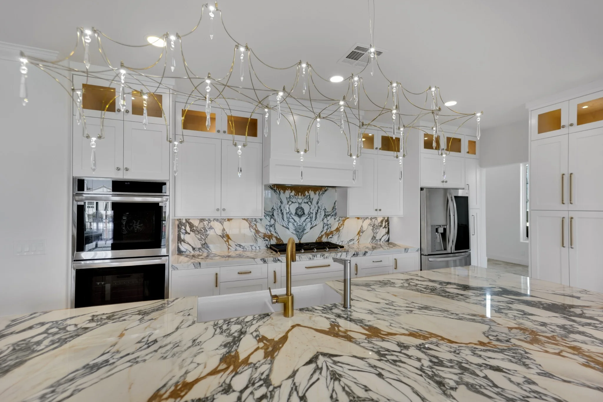 Wide view of Desert Shores custom kitchen remodel with massive marble island, stacked upper cabinets, and waterfront windows