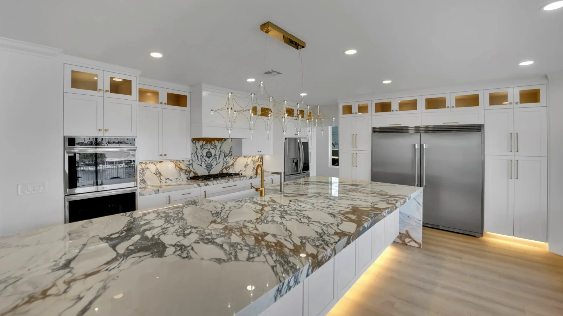Finished Desert Shores waterfront kitchen after the luxury remodel with marble island and custom white cabinets