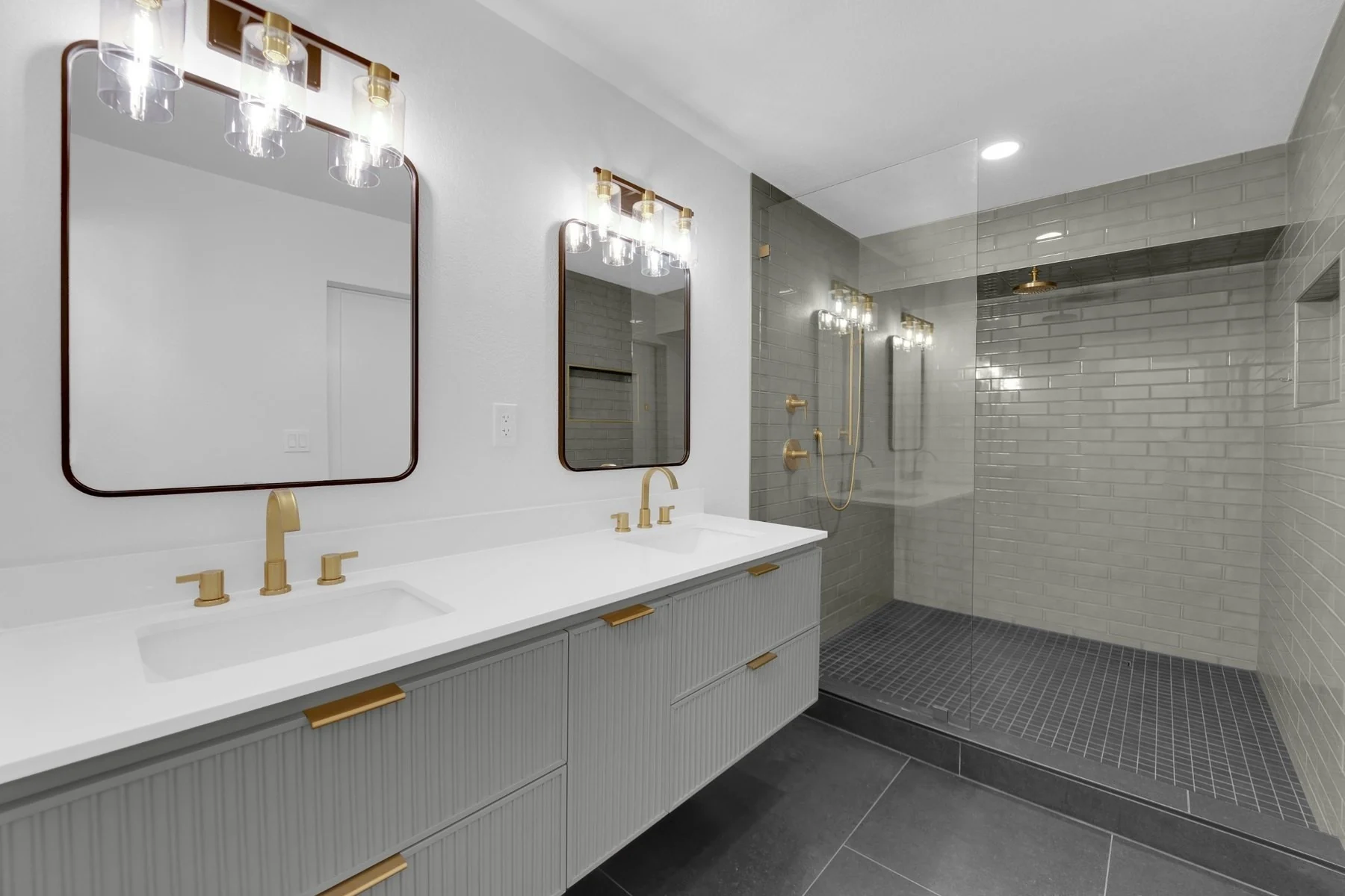 Completed Downtown Las Vegas bathroom remodel with floating gray double vanity, brushed-gold fixtures, and expanded green tile shower