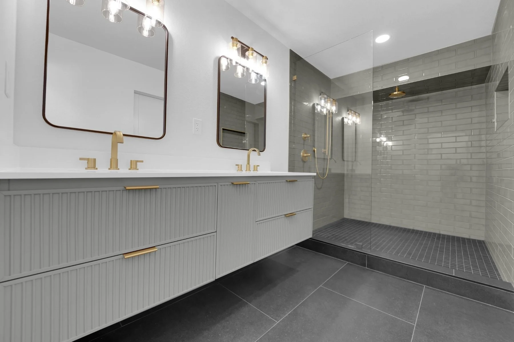 Bathroom reconstruction with gray floating vanity, graphite floor tile, and enlarged glass shower